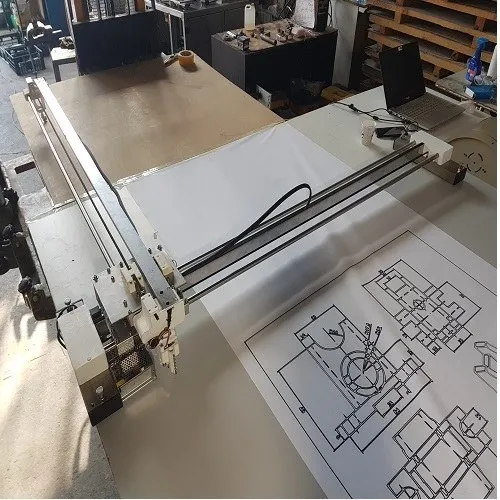 Atölyede eksenel çizim makinası, geniş bir levha üzerine teknik çizim çiziyor